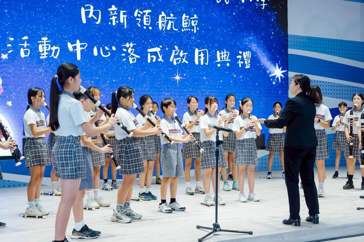 學生在「內新領航鯨活動中心落成啟用典禮」背板前合唱