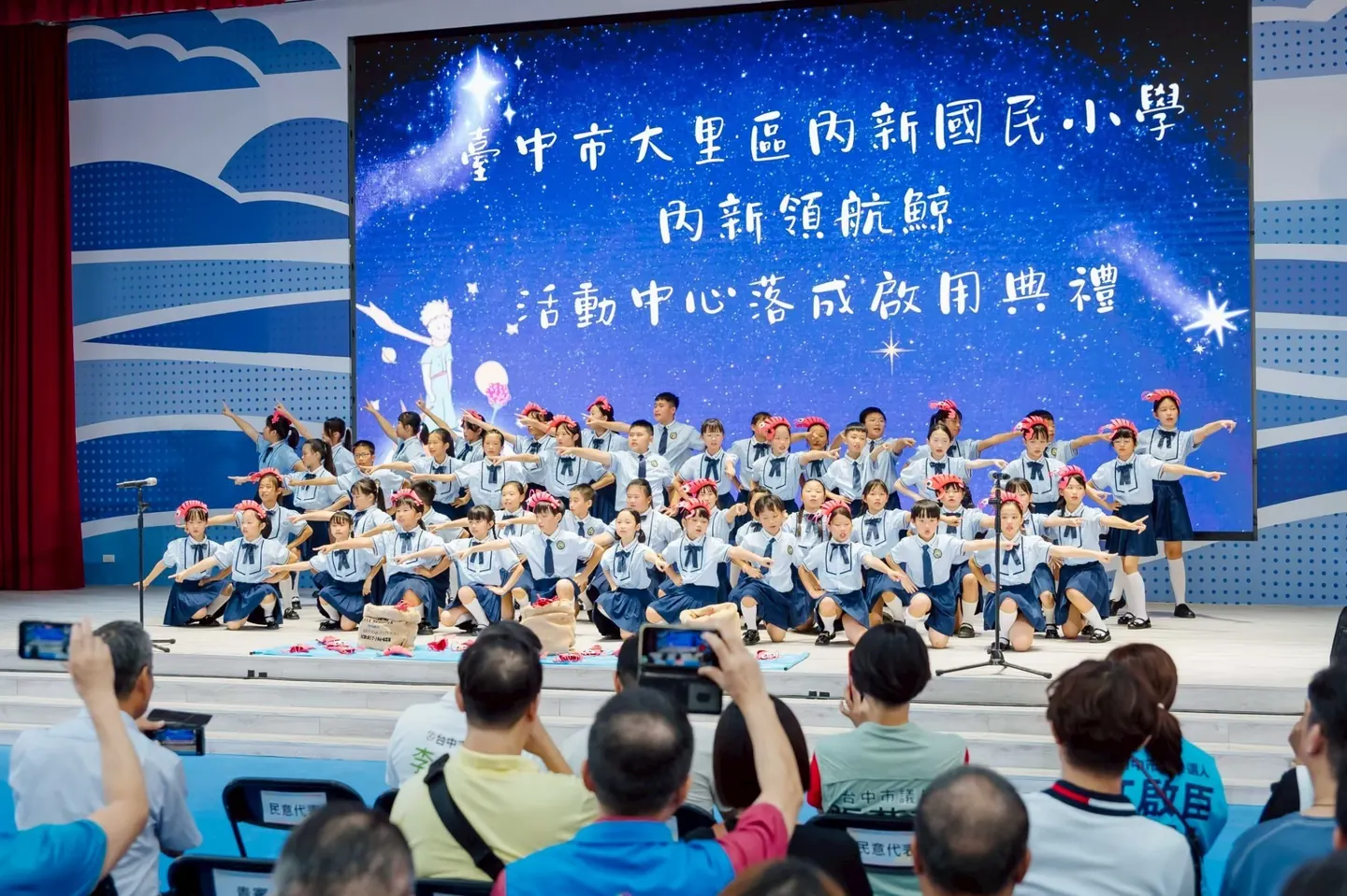 學生在舞臺上表演，家長在臺下拍照